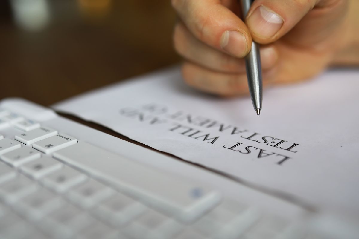 The image of a man's hand signing a paper.