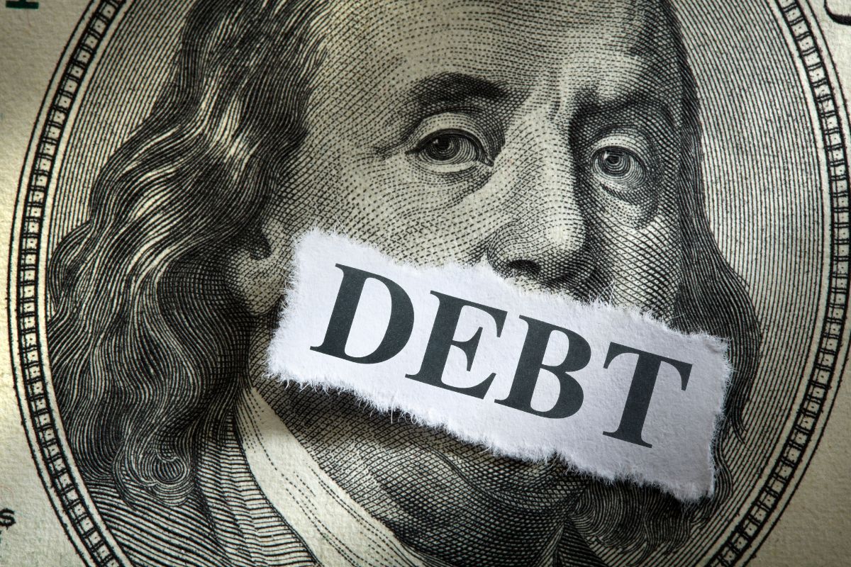 The picture shows money and debt wording on a piece of paper.