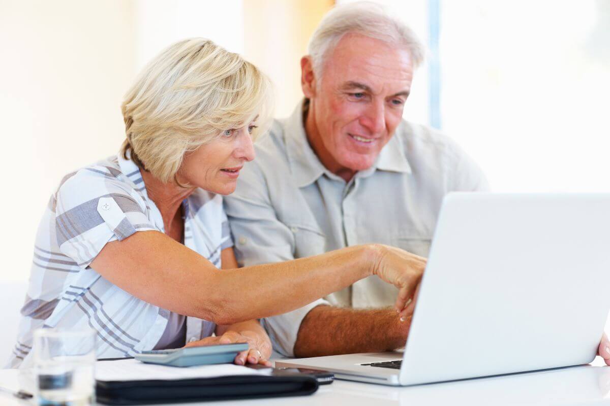 The image of a senior couple looking at a laptop while holding a calculator which means to specify how taxes, debts, and expenses should be paid to ensure the estate is settled properly and quickly.
