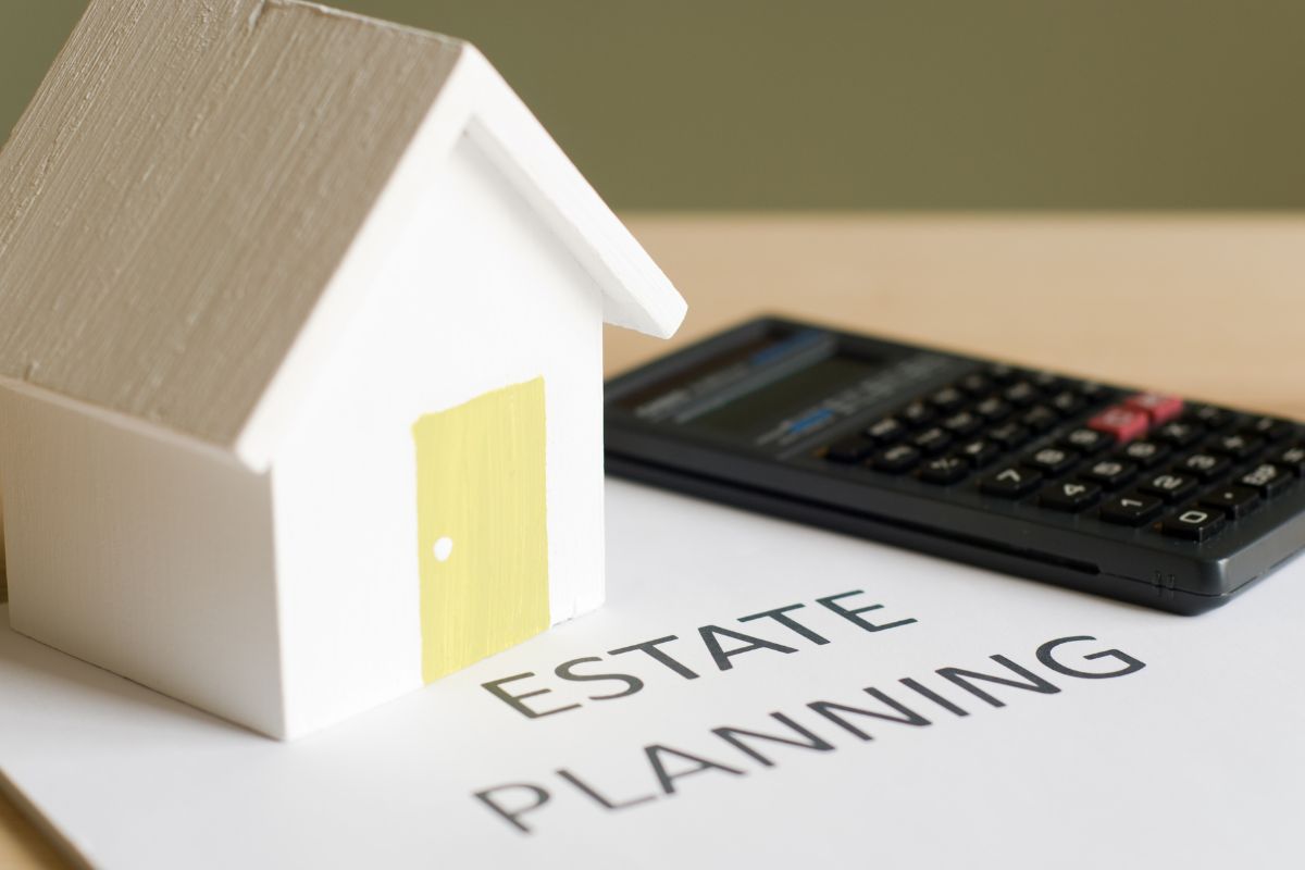 Photo of a calculator, a house, and paper with estate planning written.