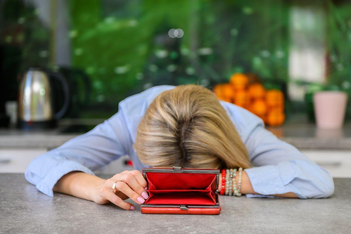 The picture tells about a girl showing off her red empty wallet while leading down which refers to saying I am broke can make you feel stuck but instead, focus on what you can do.