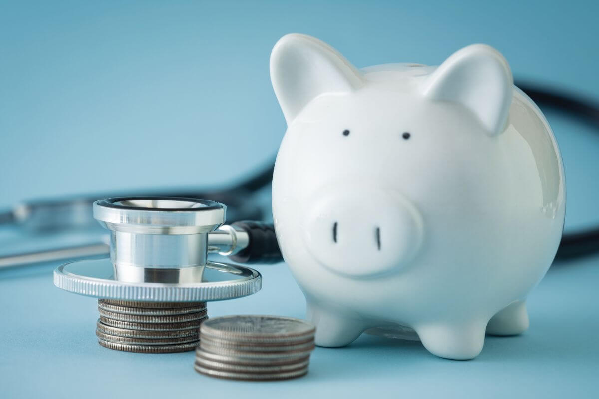 The photo shows a coins, stethoscope, and a piggy bank which means to lower healthcare costs can help reduce costs in the long run.