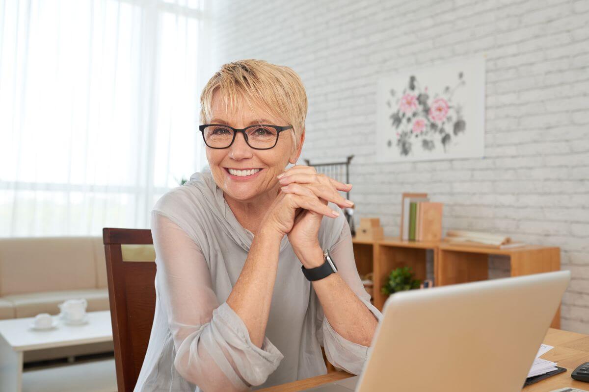 The picture tells about a senior and a laptop referring to a plan to work the typical retirement age can help reduce the need to dip into Social Security early.