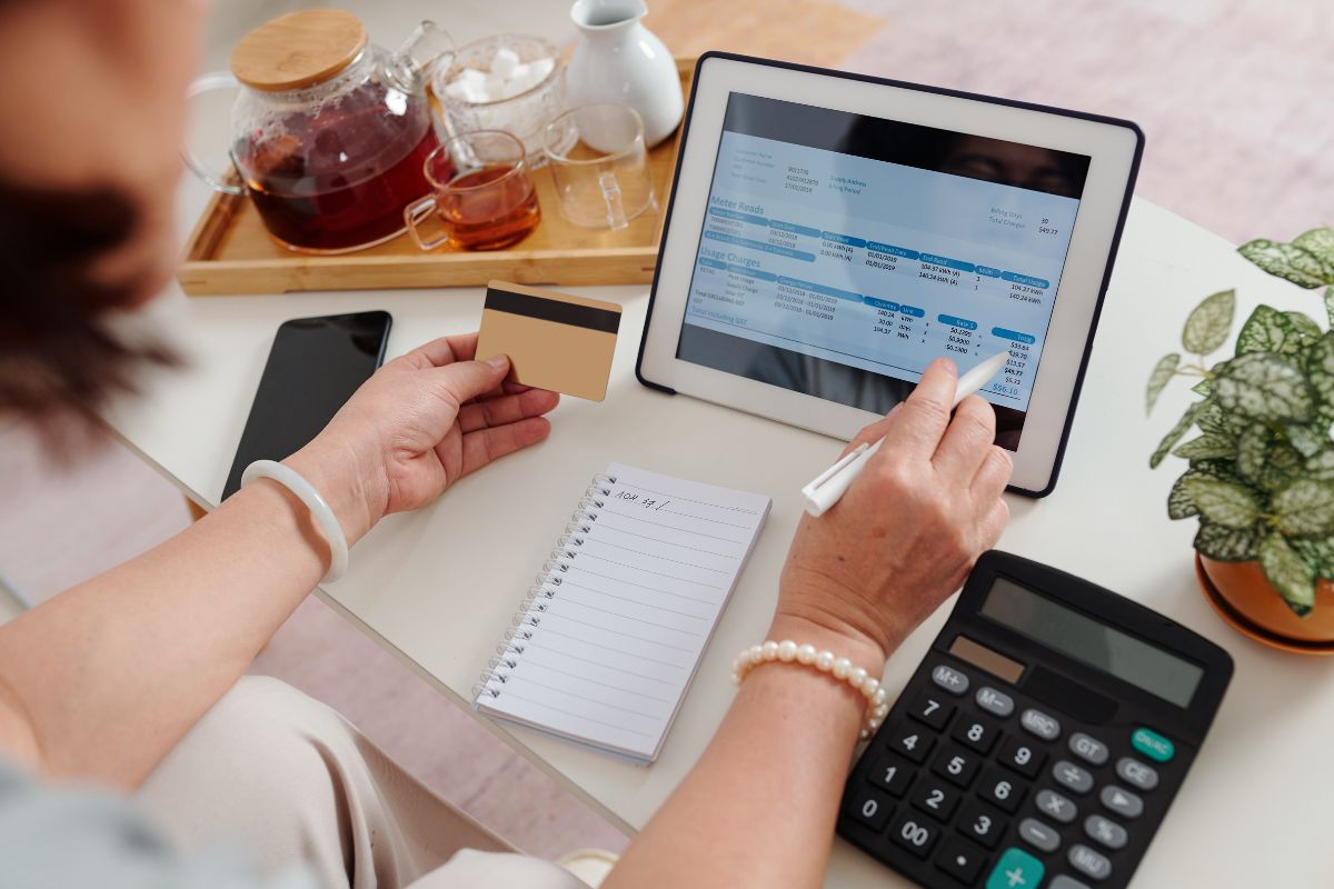 The photo shows a woman paying bills online using a credit card.