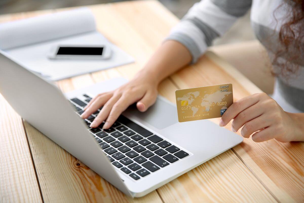 The picture of a phone, a notebook, and a girl's hand holding a credit card while typing on a laptop refers to avoiding closing old credit accounts that can contribute to the length of your credit history, which impacts your score.