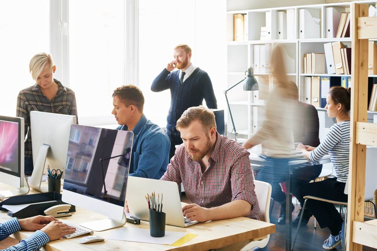 The image shows of busy people working on their laptop and computer which means to change work environment can improve focus and help new ideas flow.