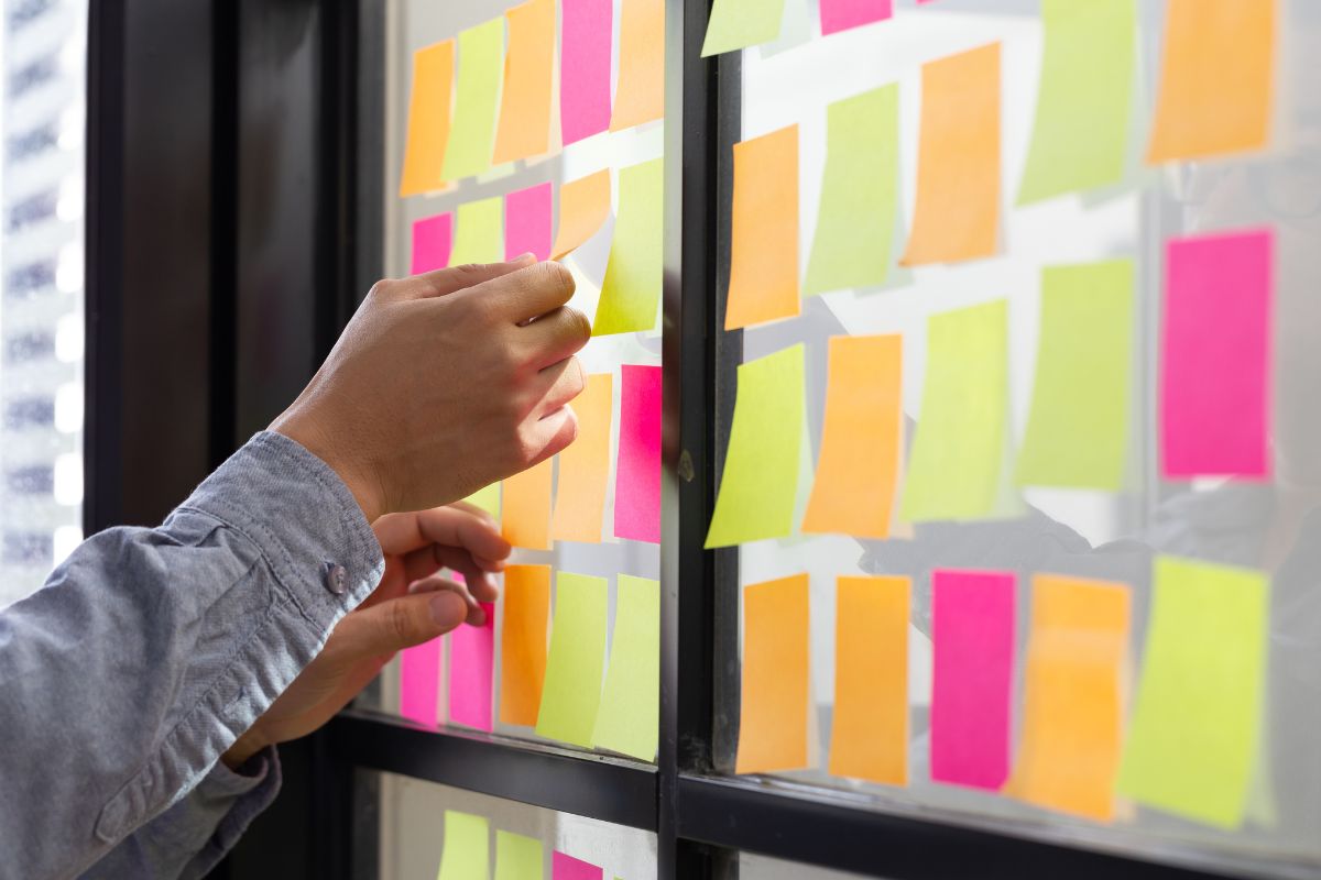 The photo shows a man's hand organizing his tasks by priorities.