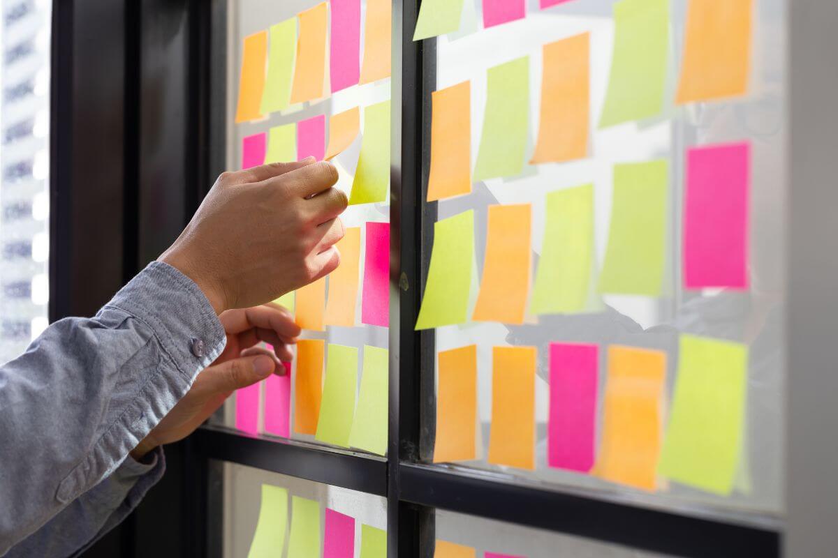 The image shows a man's hand organizing the papers into groups indicating that using the Eisenhower Matrix helps you organize your to-do list by splitting tasks into four categories.