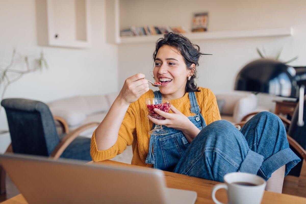 The picture of a coffee, a laptop, and a girl eating a snack indicates that rewarding yourself with something small after completing difficult tasks helps you stay consistent with your productivity.