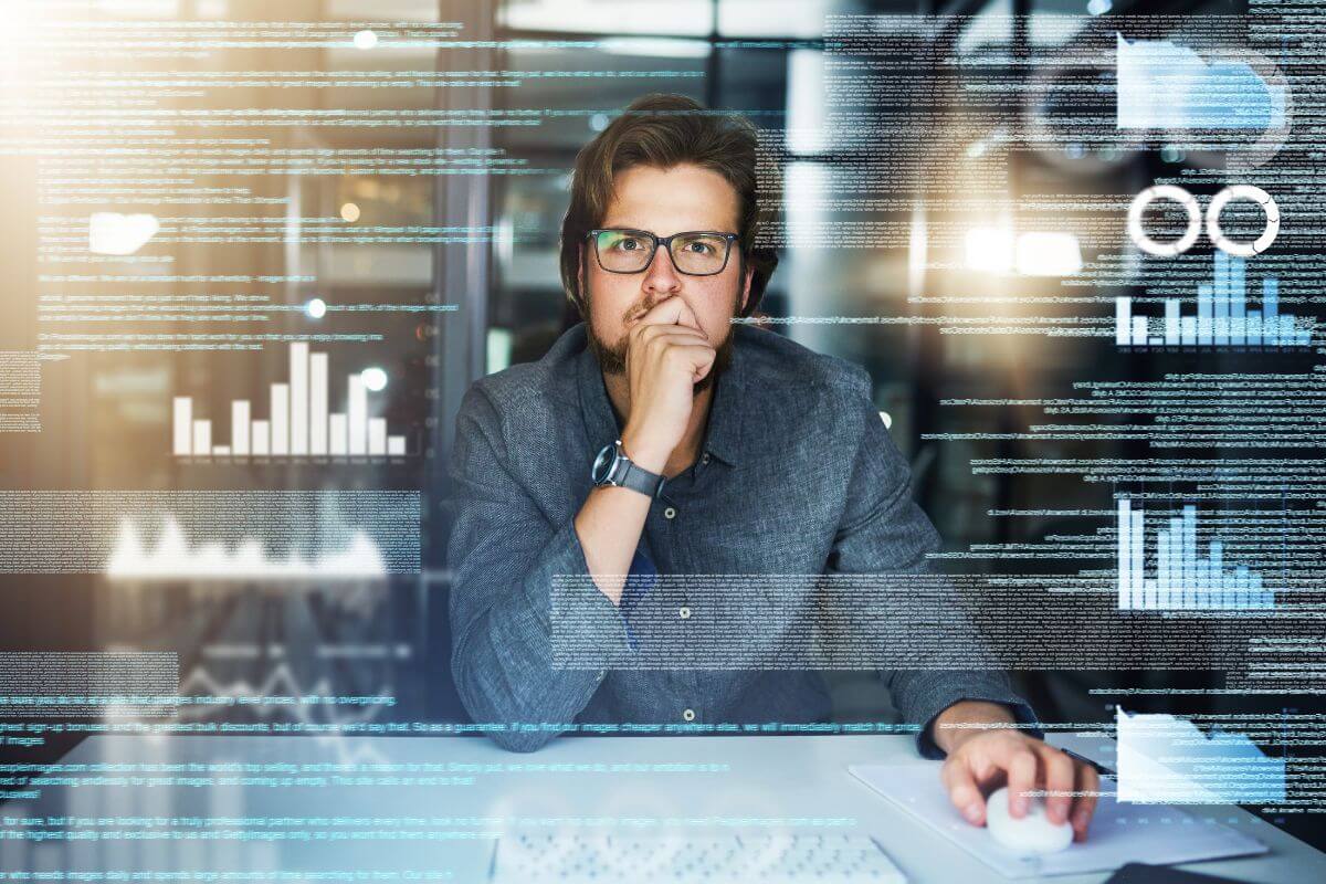 The image shows a man using a laptop while looking at the visual screen with graphs and notes which means to take your time allows you to make thoughtful decisions.