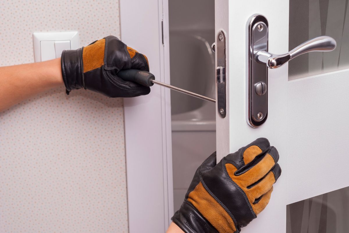 Photo of a man's hand fixing a door knob.