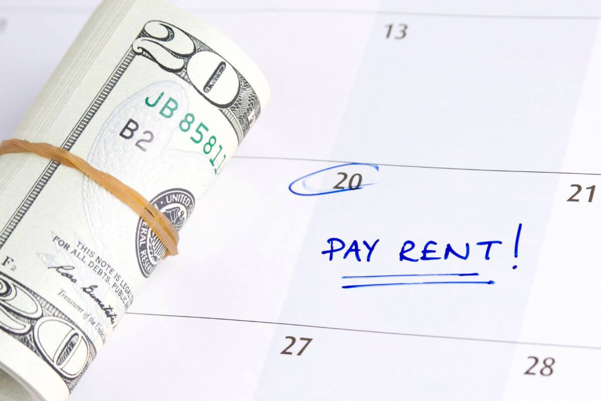The photo of rolled dollar bills and a calendar with notes indicating how to negotiate reduced rates for rent can ease pressure during uncertain times.