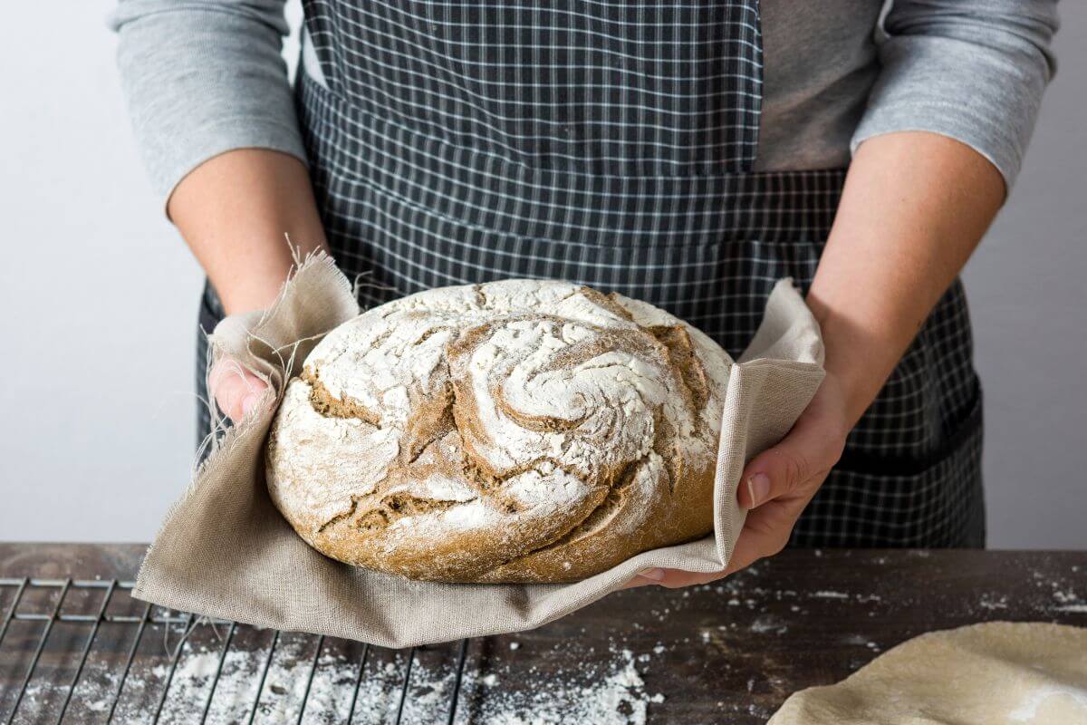 The photo tells about a girl's hand holding a baked bread referring to turn a hobby into micro-business for extra income and it's easier to save when you have a little more coming.