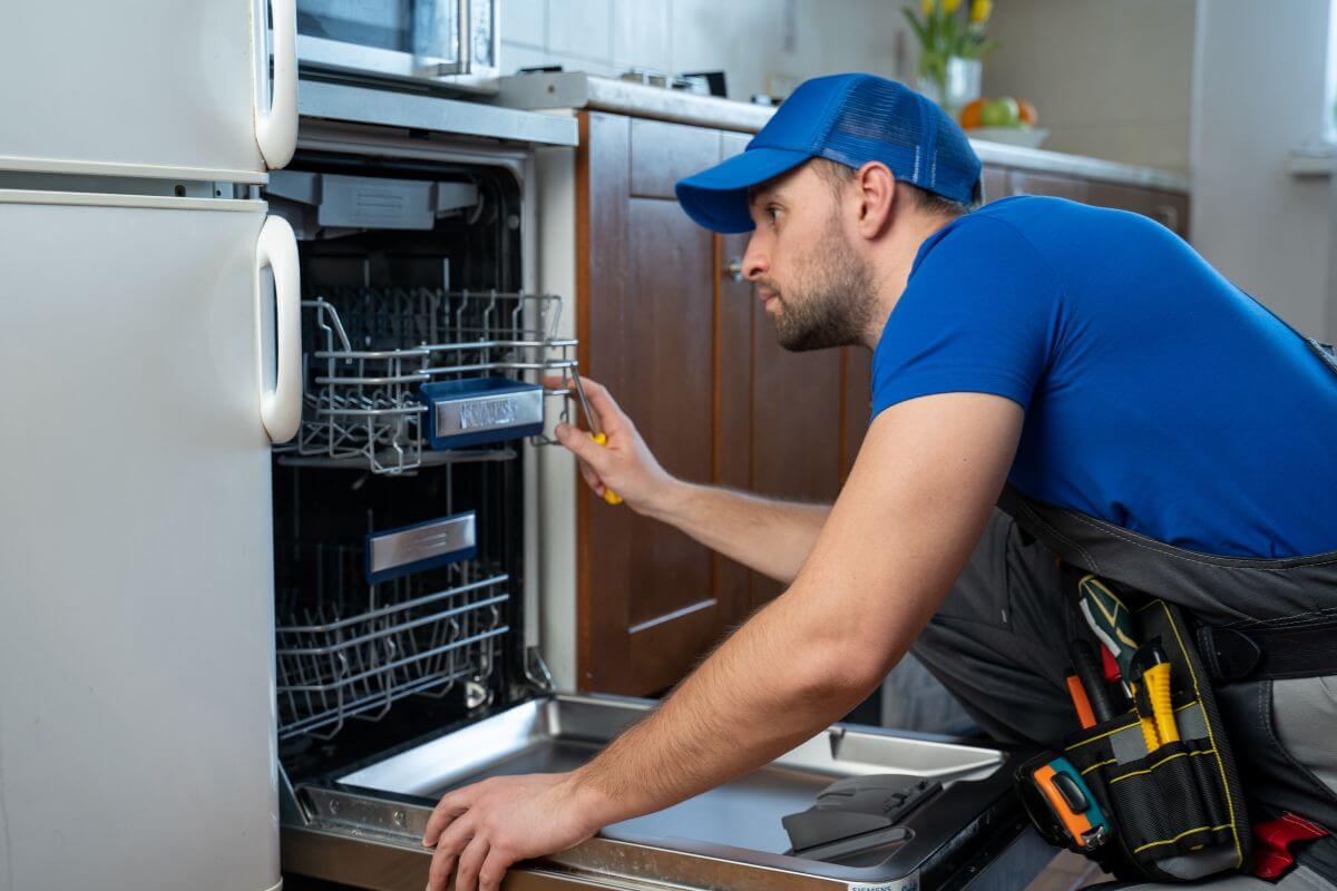The picture tells about a man repairing the dishwasher in the kitchen which means to offer do maintenance in exchange for rent discounts to reduce your costs without impacting your savings.