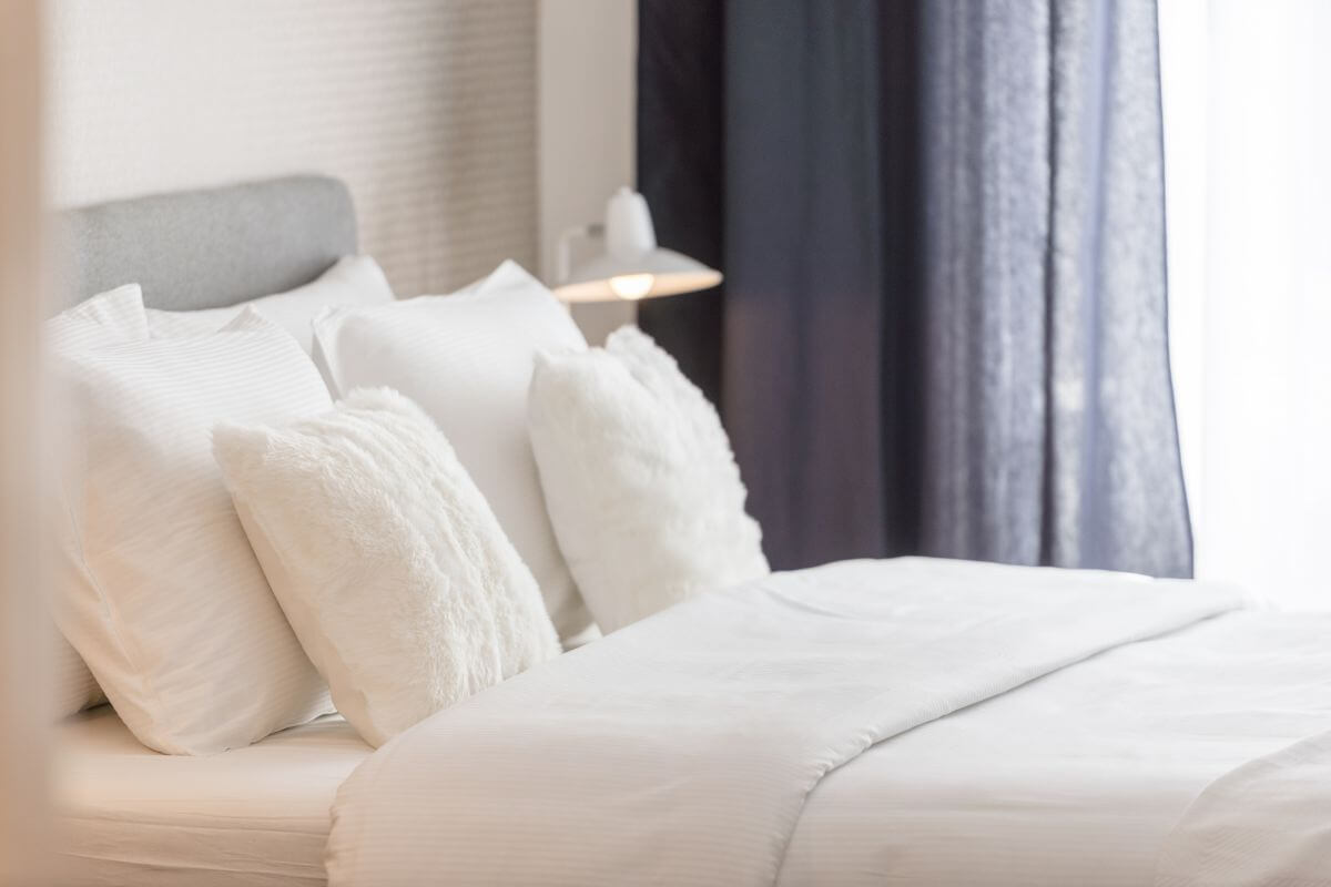 The image shows a clean bedsheet, pillows, and bed indicating to rent out a room to help with rent or mortgage payments.
