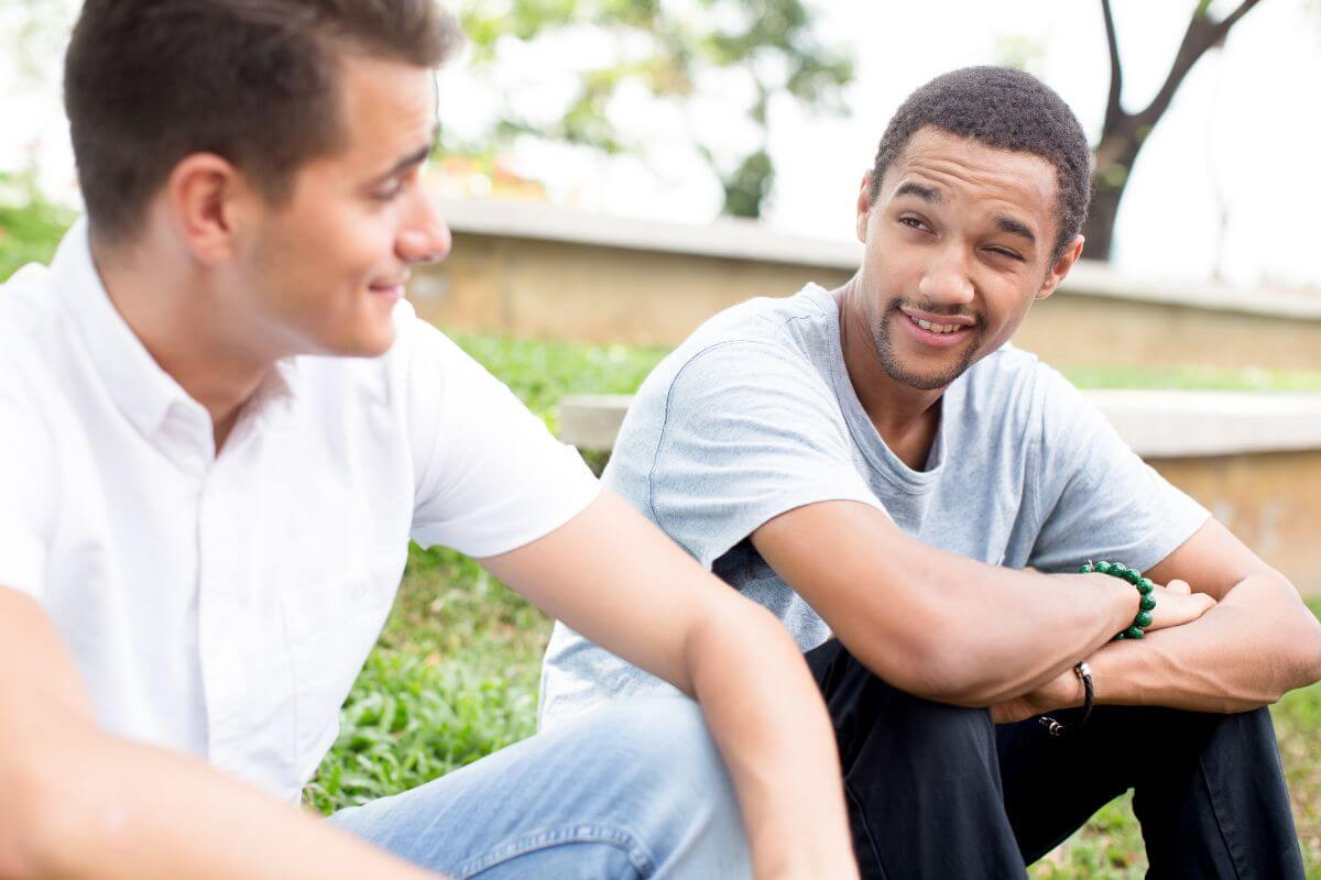 The photo tells about two men talking to each other at the park referring to ask friends if you can stay with them during hard times can help you cut housing costs while you work to stabilize your finances.