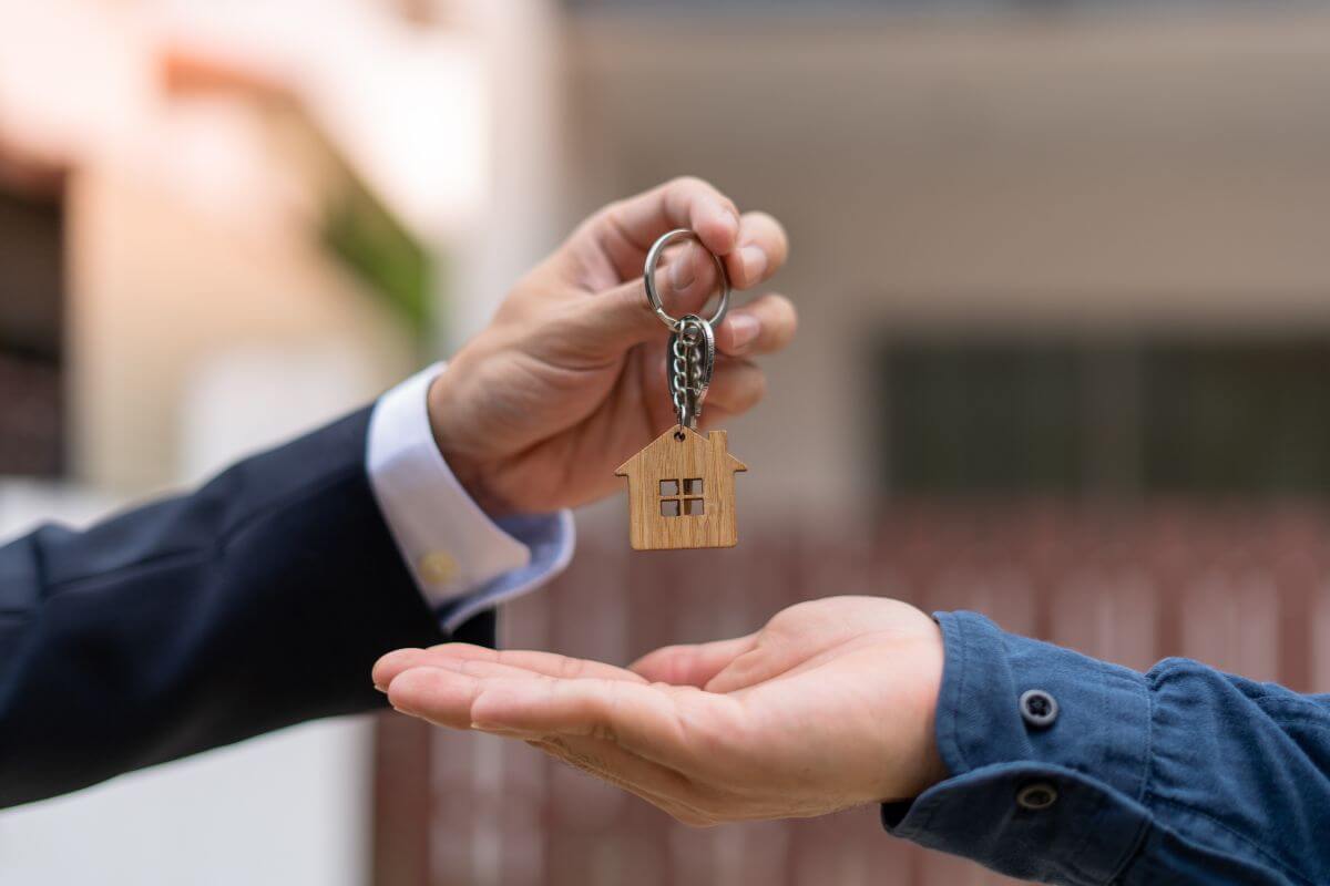 The photo tells about a man's hand giving the keychain house to a man's hand referring to offering your landlord upfront payments for future rent and being willing to negotiate.