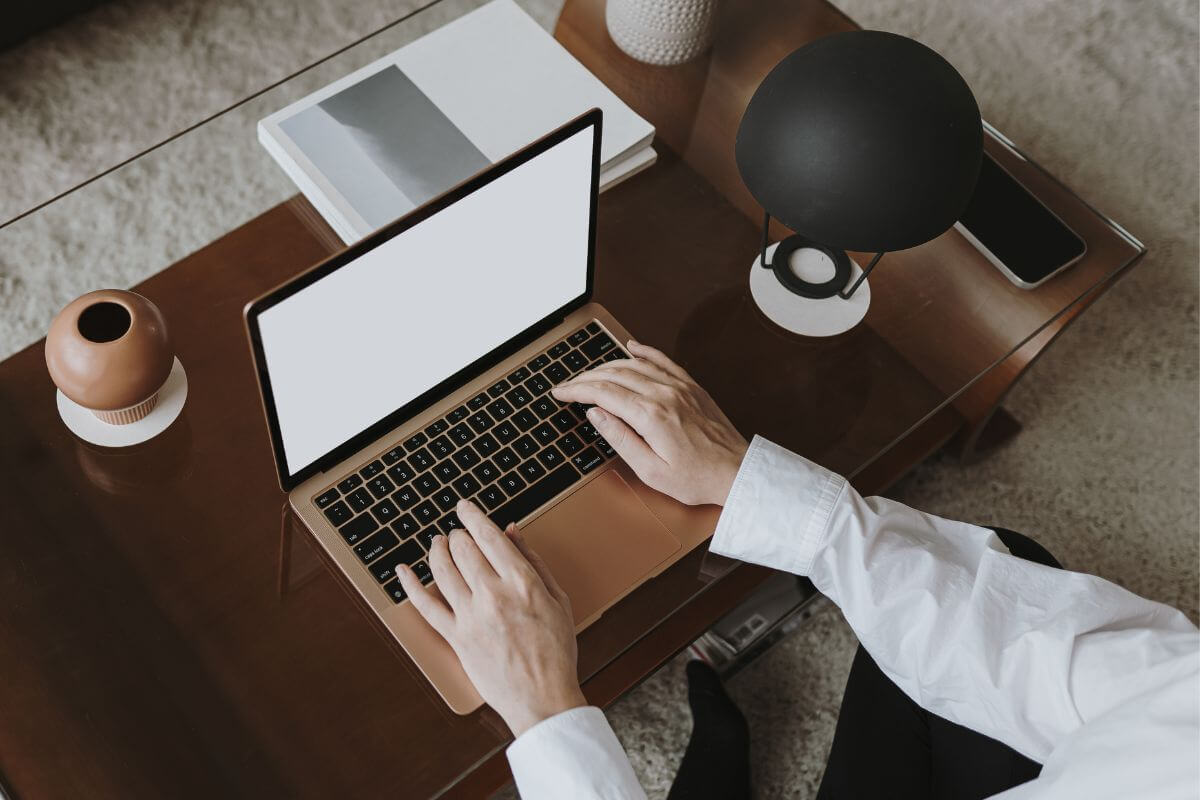 The picture tells about magazines, lamps, a phone on the table, and a man's hand using a laptop refers to finding more ways to lower your fixed expenses can help ease the pressure of rent or mortgage payments.