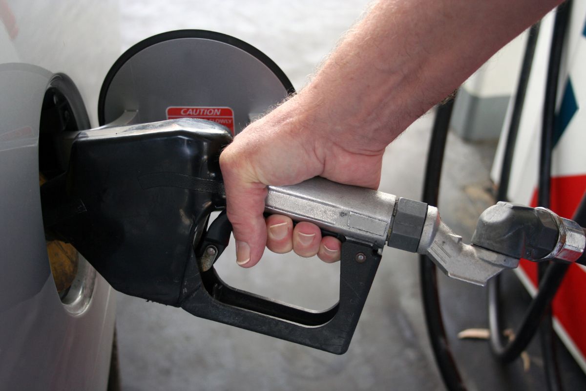 The man's hand refilling the car with fuels which means ultra-premium gas can throw money away, regular work and save more.