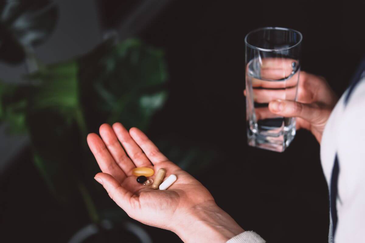 The photo of a girl's hand holding a glass of water and capsules referring to trendy health supplements can drain your budget, sticking to proven essentials can save more money for real health needs.