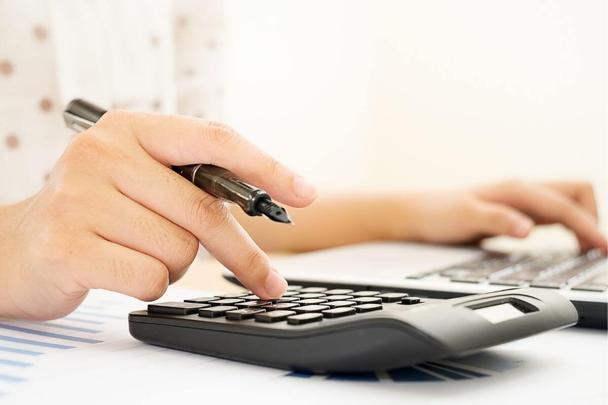 The photo shows a girl's hand using a laptop and a calculator to help teens see where their money goes.