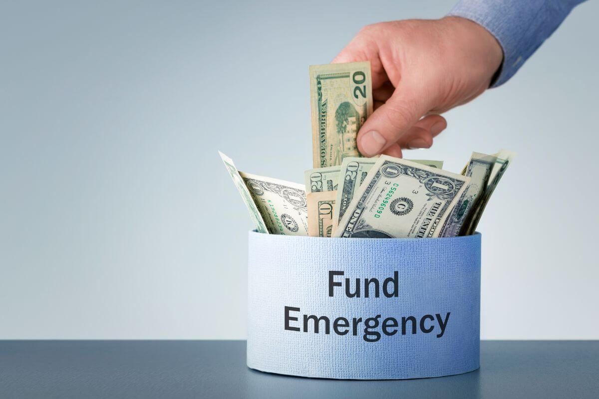 The picture of a blue container with dollar bills with dollar bills and a man's hand putting money on it indicates to run mock financial emergencies to teach teens how to plan.