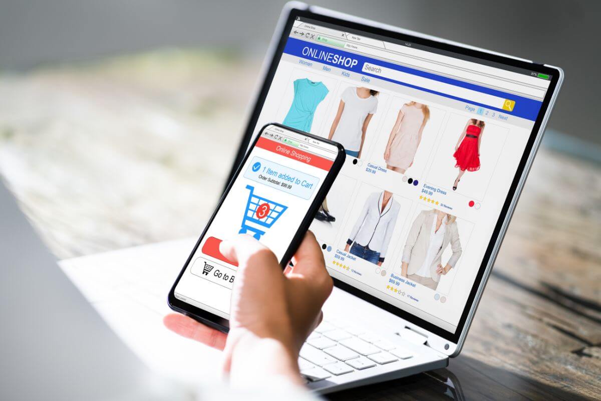 The picture tells about a laptop with a screen display and a girl's hand using a phone which means to set up an E-commerce side hustle helps teens learn business basics.