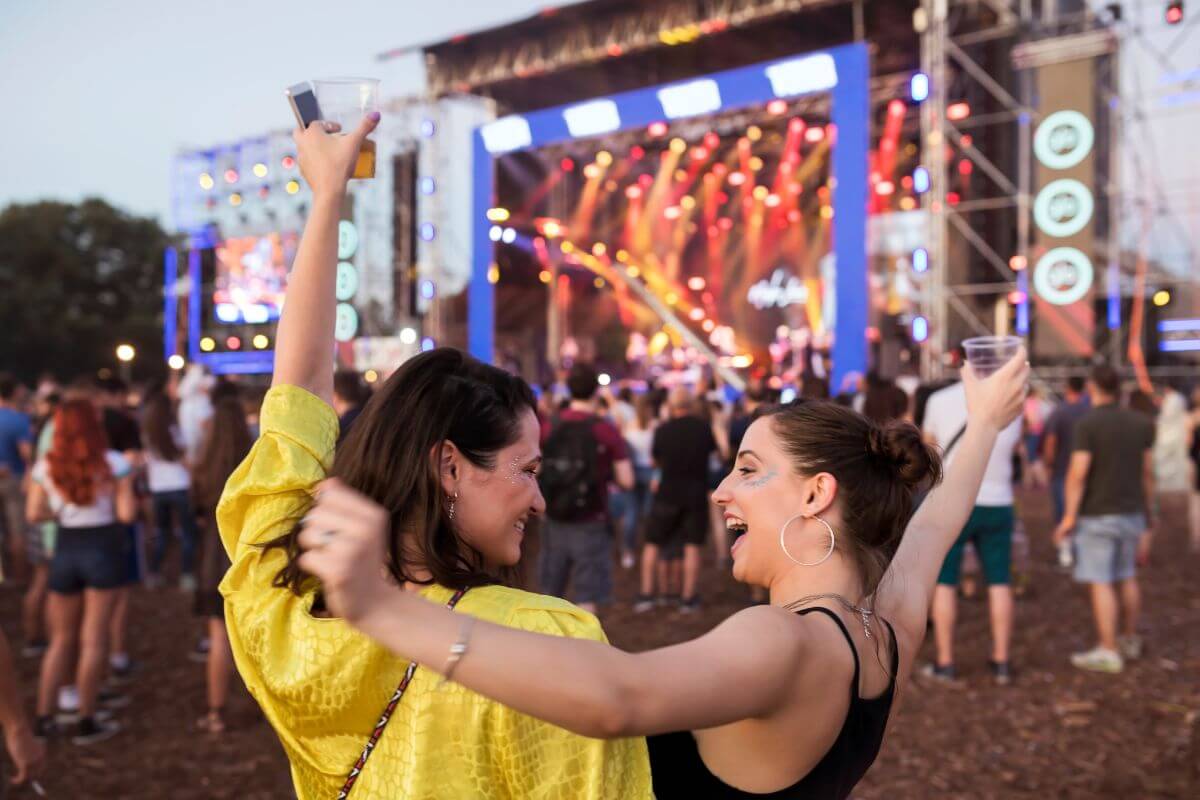 The photo shows tow girls enjoying the concert together with the other people which means challenging yourself to have a $0 entertainment budget and find joy without breaking the bank.