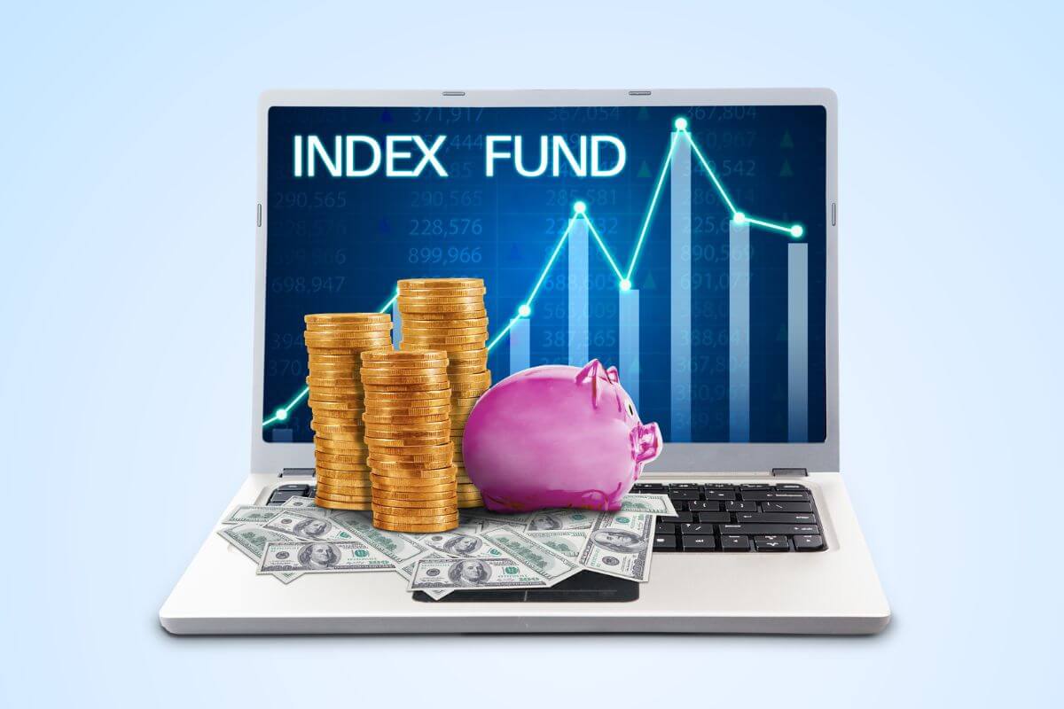 The picture tells about coin stocks, a piggy bank, dollar bills, and a laptop with a screen display indicating that investing aggressively in index funds is a proven way to build wealth over time.