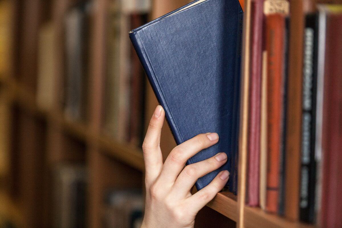 The photo tells about a girl's hand grabbing a book indicating that using free community resources like libraries helps you live within your mind.