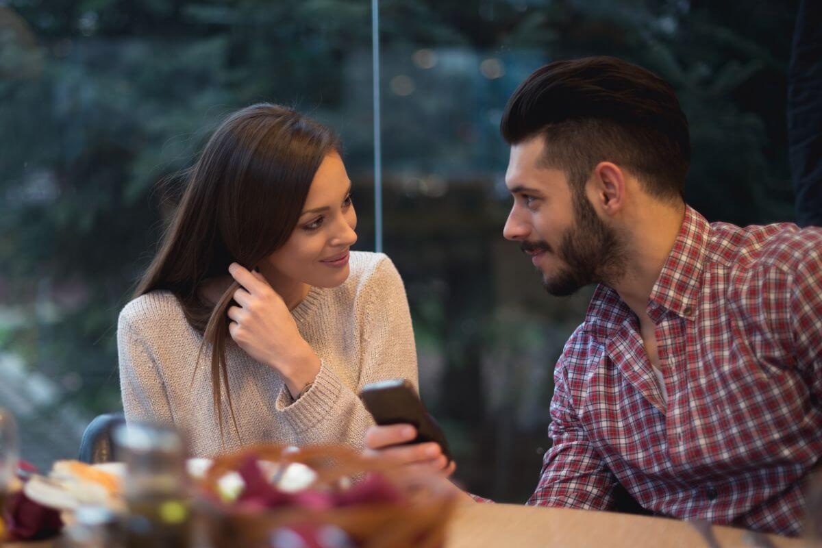 The picture shows a man showing his phone to the girl indicating to avoid dating anyone who doesn't share your financial goals making it easier to build wealth as a team.