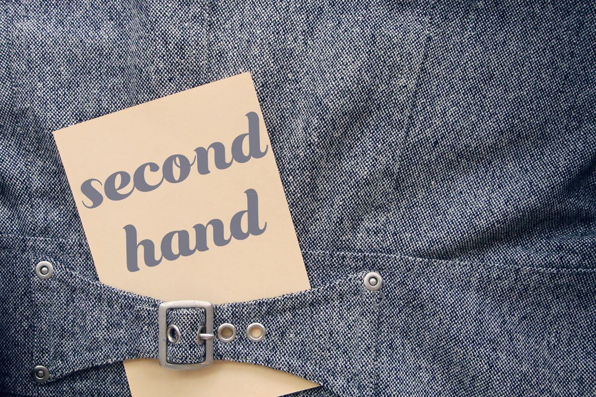 The image of clothes with a piece of paper with notes referring to buying everything secondhand reduced costs and frees up money for investments. 
