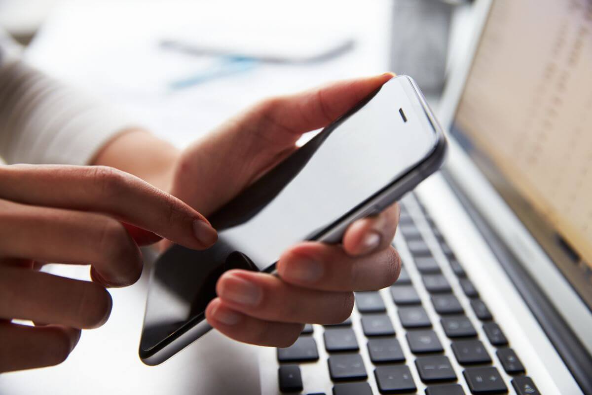 The picture shows a laptop and a girl's hand using a phone which means switching to a prepaid home plan to slash monthly costs can save you a lot of money every month. 