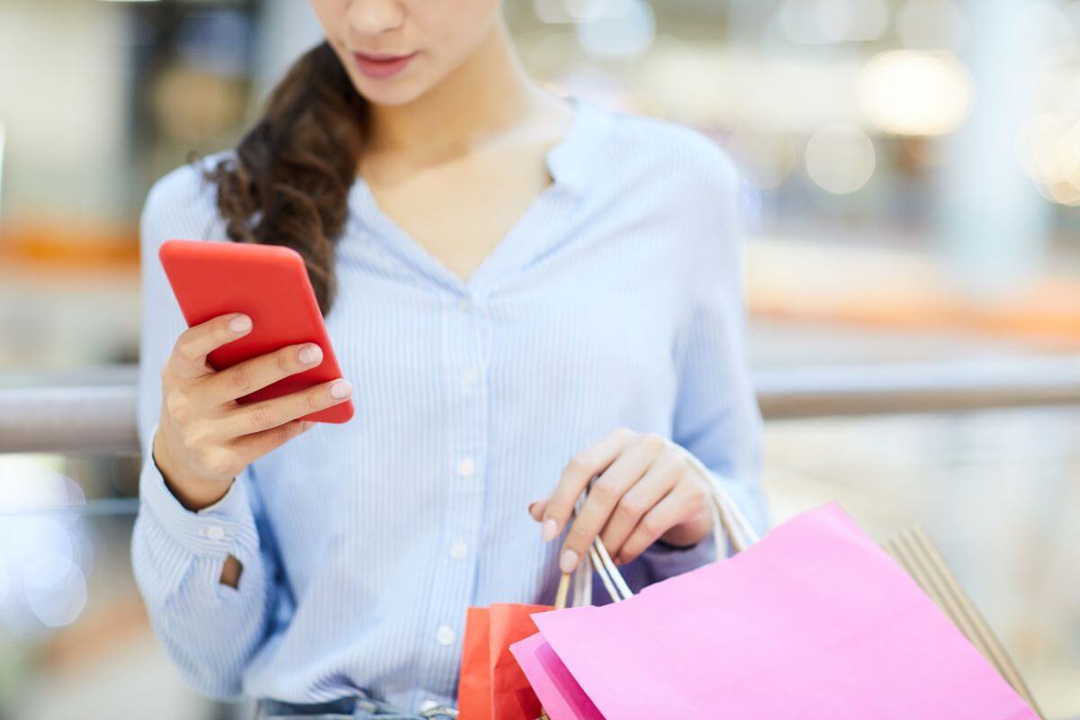 The photo tells about a girl carrying shopping bags while using a phone indicating to mystery shoppers that luxury brands combine good pay with enjoyable experiences.