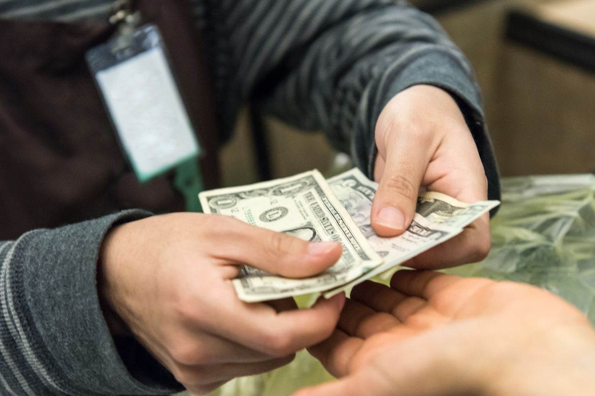 Image shows a man paying cash.