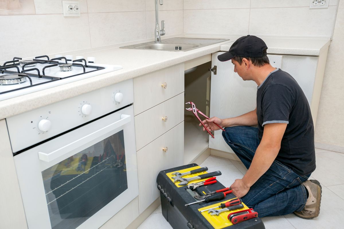 The photo shows a man repairing the sink.