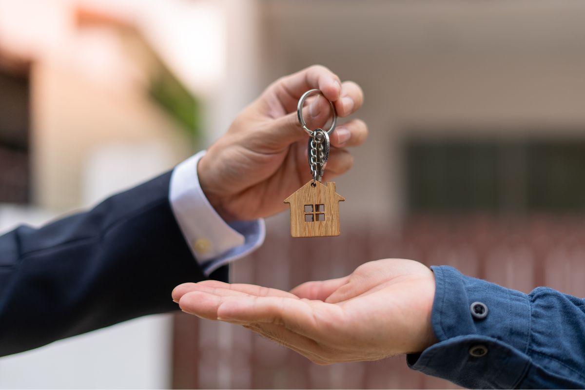 Picture of a landlord hand-giving a house key to the occupant.