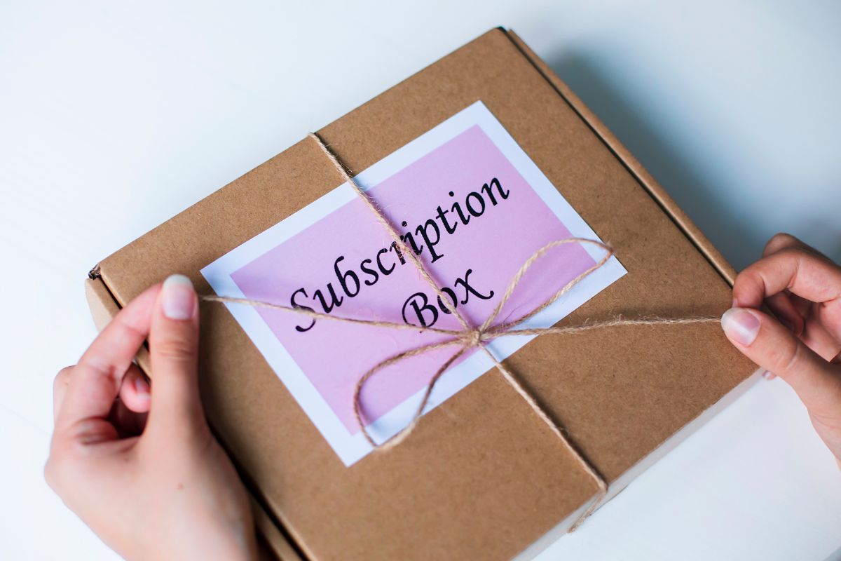 Picture of a woman's hand unboxing a subscription box.