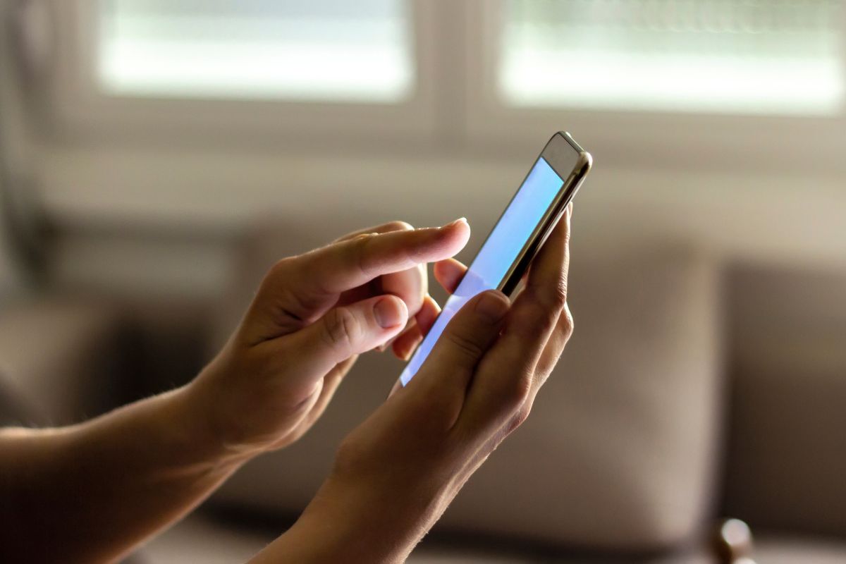 The photo shows a woman's hand using a phone.