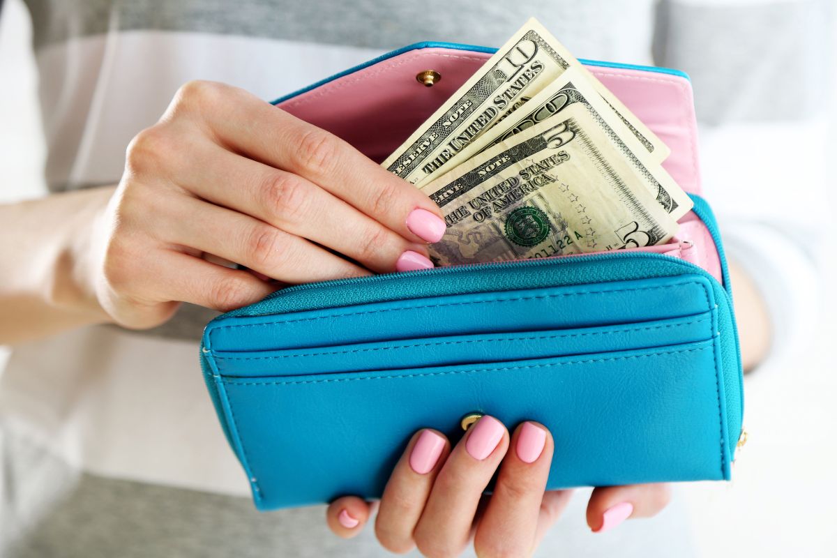 Image of a woman's hand holding a wallet with money.