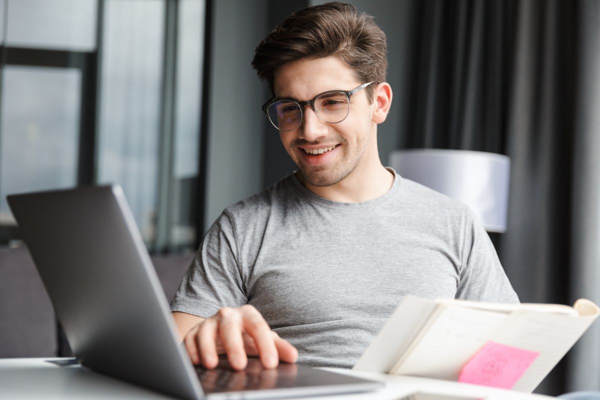 The photo shows a man using a laptop.
