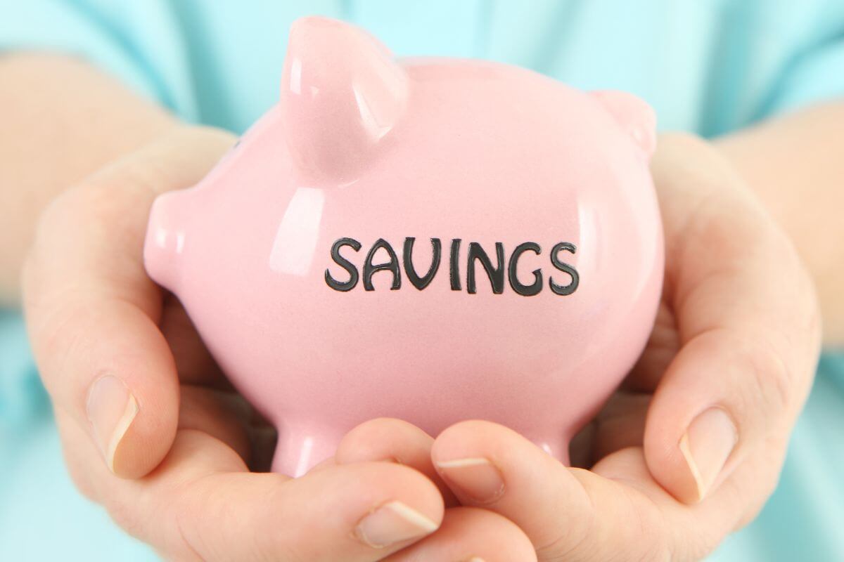 The image tells about a girl's hand holding a piggy bank with notes which means that saving at least 10% of your income helps build a safety net.