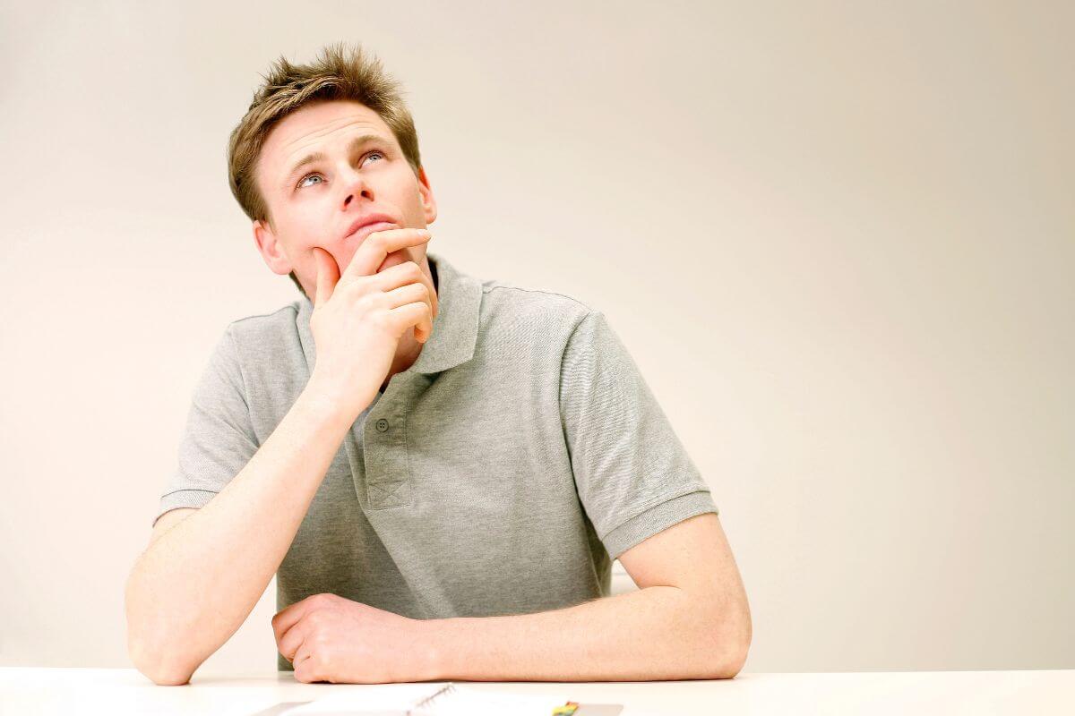The image tells about a notebook on the table and a man thinking which means to visualize your future self thriving to stay focused when challenges arise and can keep you moving forward.