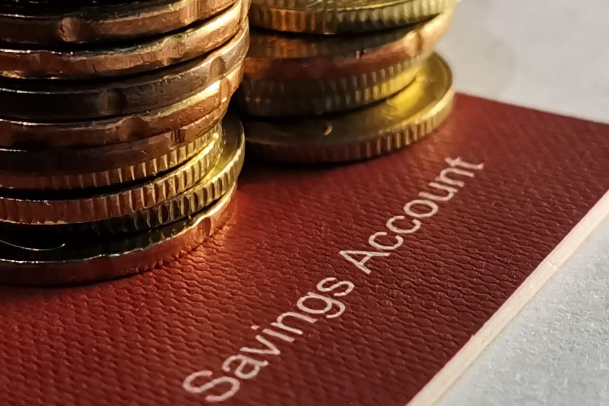 The image shows coin stocks and a book bank refers to automating savings into high-yield savings accounts makes it easier to reach your financial goals.