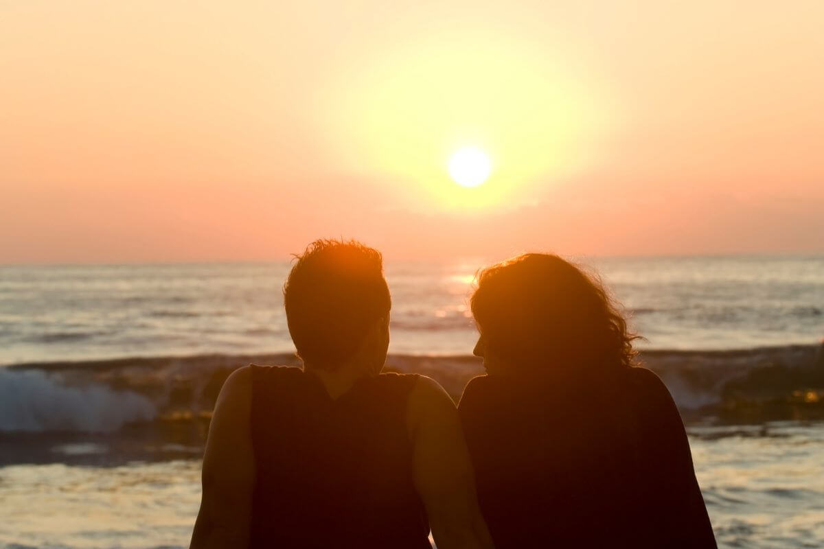 The picture shows a couple at the seaside referring to watching the sunset is perfect for creating quiet moments that feel meaningful.