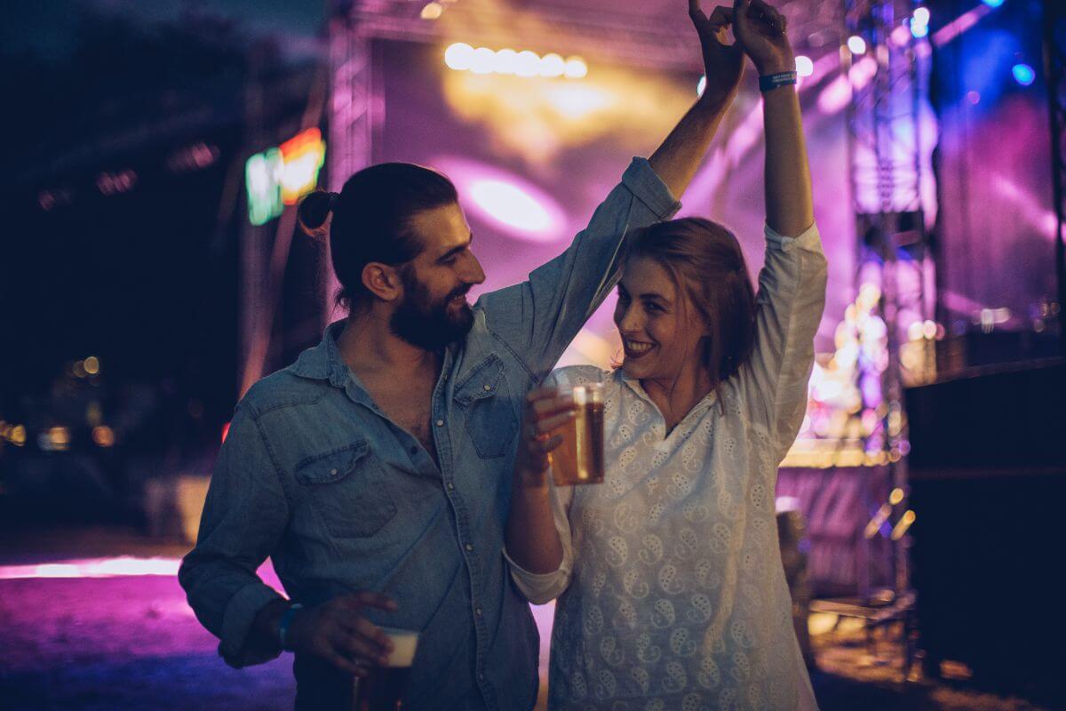 The picture of a couple with their drinks dancing together which means attending a local free event is a great way to have fun while staying on a budget. 