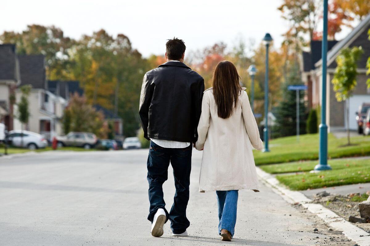 The photo shows a couple walking on the street along the houses which means exploring a nearby neighborhood you've never visited to create memories without going far or spending too much.