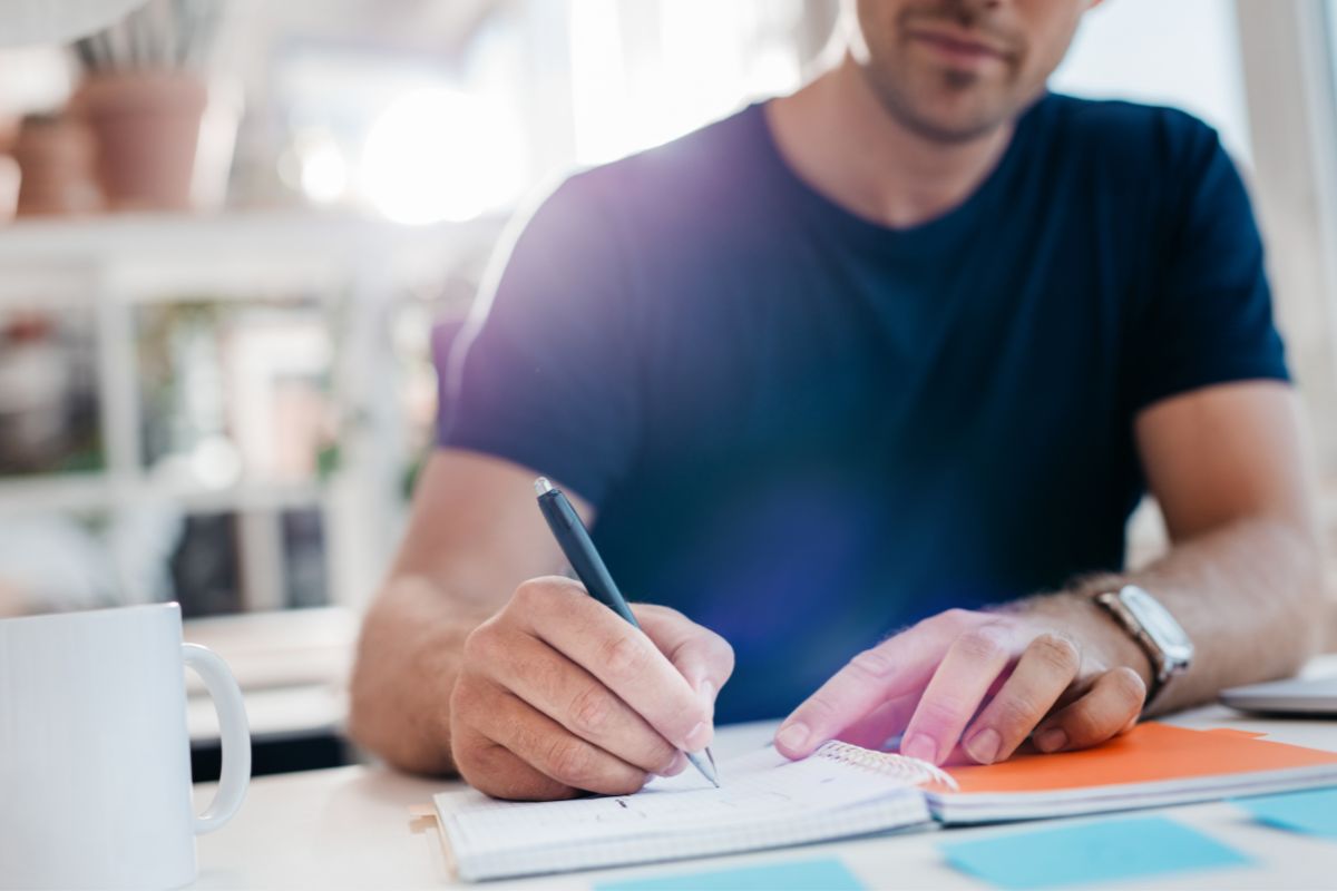 Image of a man writing down his income sources.