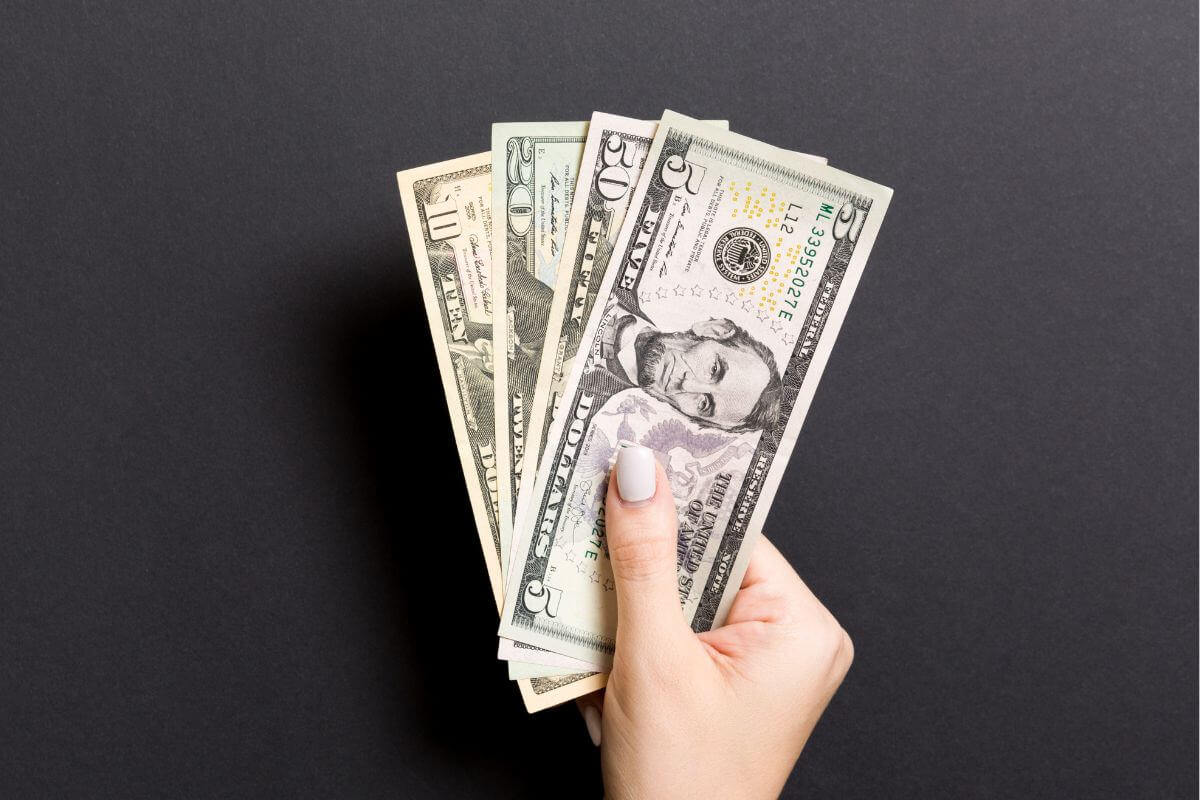 The picture shows a girl's hand holding dollar bills which means that using cash to avoid overspending helps you stick to what's in your budget.
