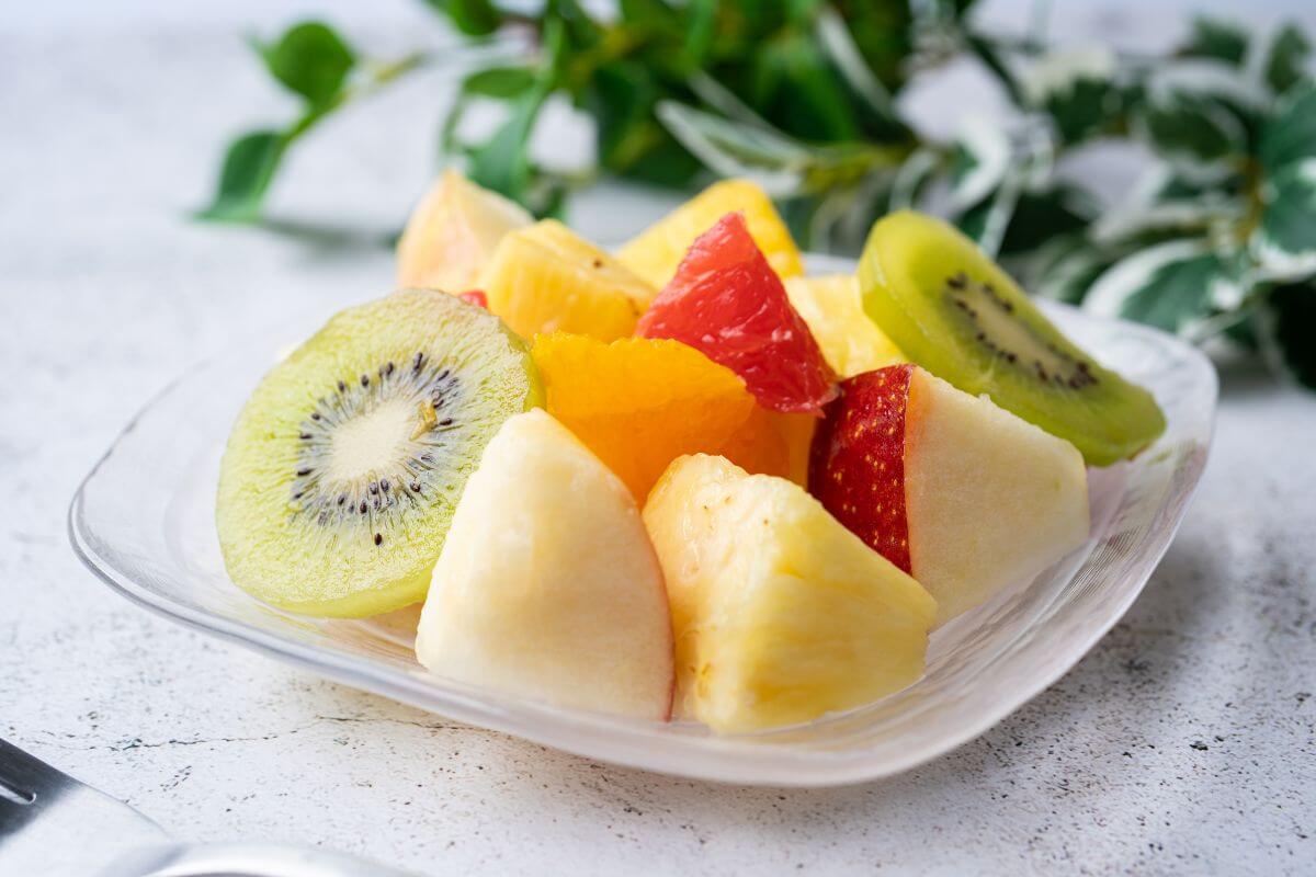 The picture of a plant and a plate with different fruits indicates that pre-cut fruits and vegetables cost extra, buying whole produce and cutting it yourself saves a lot on your grocery budget.